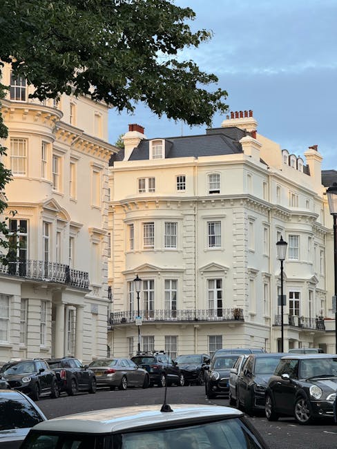 Image showing a row of elegant white residential buildings with classic architectural features, including bay windows, decorative mouldings, and small balconies with black wrought iron railings. In fr
